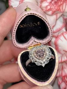 Dettaglio dell'anello con diamante a cuore rosa in scatola di velluto e garofani