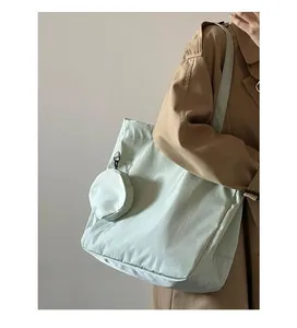 Detail of mint green nylon tote bag with small detachable round pouch on a model