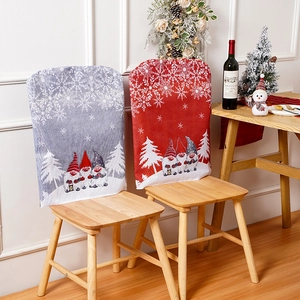 Two festive Christmas chair covers with gnome and snowflake patterns in a cozy dining setting