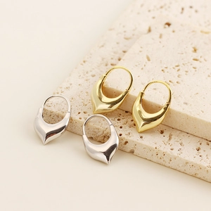 Macro detail of high-polish heart hoop earrings in gold and silver finish on stone