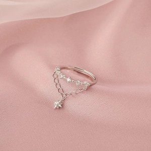 Detailed macro shot of silver star pendant on a chain ring over pink silk background