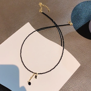 Macro view of black beaded tassel necklace with geometric crystal pendants and gold clasp