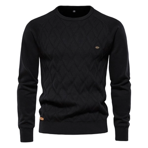 Detailed view of black knitted sweater with diamond texture and metallic logo plaque