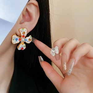 Close-up of vintage flower clip earrings with pearls and colorful gems on model's ear