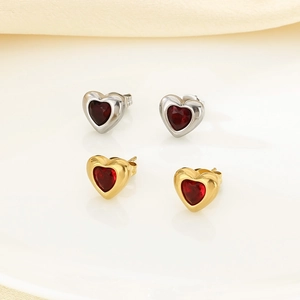 Detail of vintage heart earrings in gold and silver finishes with red stone inlays