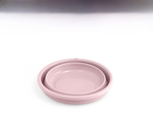 Top view of a compact pink foldable washbasin in fully collapsed state for easy storage