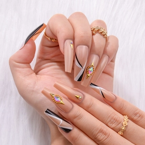 Detailed view of long coffin press-on nails with geometric patterns and gold diamonds