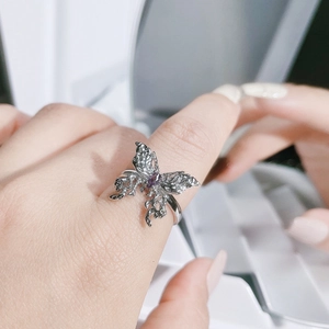 Close-up of silver butterfly ring with purple gemstone and hollowed wing details