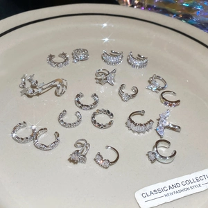 Collection of silver-tone ear cuffs with star and butterfly motifs on a beige ceramic plate