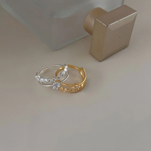 Detail of silver and gold crown-shaped S925 rings with zircon on a neutral base