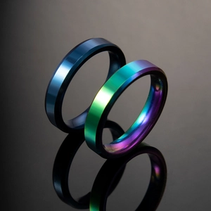 Polished titanium steel rings in deep blue and iridescent rainbow colors on dark mirror