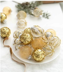 Close-up of golden and transparent 6cm Christmas balls with glitter and stripes on white plate