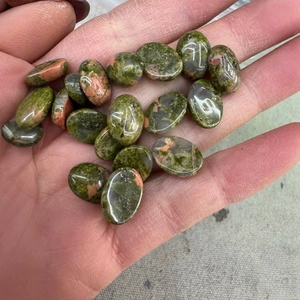 Polished oval unakite stone cabochons for DIY jewelry making displayed on a hand