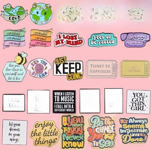 Detail view of colorful enamel pins collection with inspirational English text on pink background