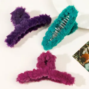 Three plush faux fur hair claws in purple, green, and rose red on a white plate
