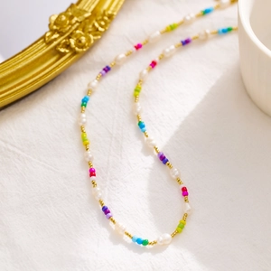 Detail view of colorful beaded necklace with pearls on a textured white fabric background