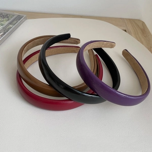 Close-up of four stacked colorful leather headbands in brown, red, black and purple