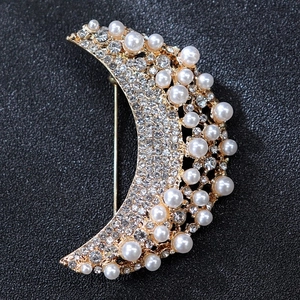 Detailed close-up of a moon-shaped brooch with golden alloy base and white pearls