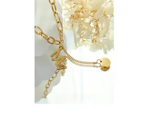Macro shot of gold-plated M letter pendant with round tag on layered steel chain