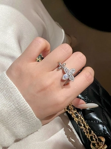 Macro detail of silver floral ring with zircon stones worn by a model in soft light