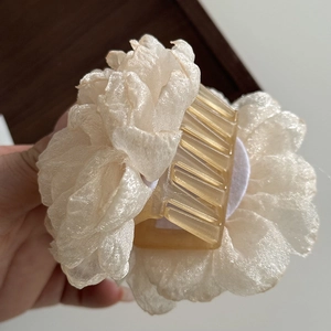 Detailed close-up of a beige organza floral hair claw clip with transparent amber base