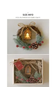 Close-up of a lit wooden house ornament inside a snowy Christmas wreath with red berries