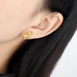 Modern irregular crumpled gold stud earrings with a unique lava texture on a model