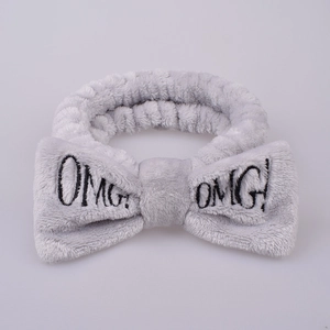 Detail shot of grey plush headband featuring OMG embroidered letters and soft bow texture