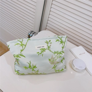 Détail de broderie jacquard oiseau et étiquette 'simple wish' sur trousse vert clair
