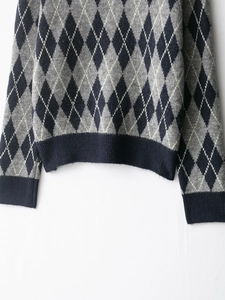 Detail of argyle pattern knit sweater with navy blue ribbed hem and cuffs for winter