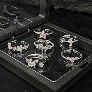 Detail of six adjustable silver rings with pink zircons and butterfly star motifs