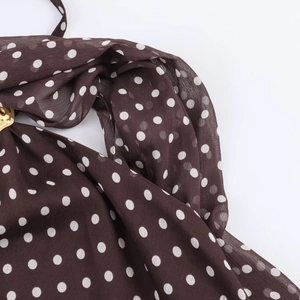 Detail of coffee brown polka dot chiffon fabric with a gold circular metal buckle