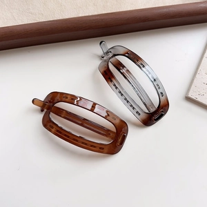 Close-up of polished oval hair clips in amber and translucent grey acrylic material
