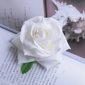 Close-up of white fabric rose hair clip with realistic silk petals and green leaves