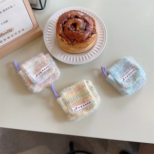 Detailed view of plush knitted mini headphone pouches in macaron colors on a table