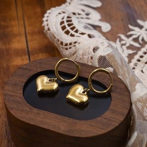 Polished gold heart drop earrings on a vintage wooden jewelry box with lace detail