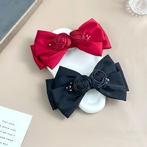 Detail of red and black satin rose hair clips with subtle rhinestone embellishments