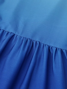 Gros plan détaillé montrant la texture du tissu dégradé bleu et les coutures de la robe