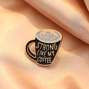 Cartoon coffee cup enamel pin with Strong Like My Coffee text on champagne silk fabric