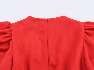Détail d'une robe rouge en suédine avec manches bouffantes et fermeture invisible