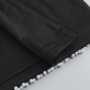 Close-up of elegant white pearl bead detailing on the edge of a black evening dress fabric