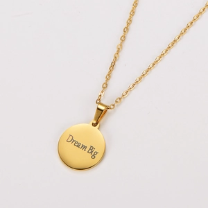 Detail of 18k gold plated necklace featuring a Dream Big engraved circular pendant
