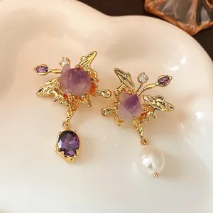 Asymmetric butterfly earrings with purple crystals and freshwater pearl in gold finish