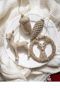 Vue détaillée d'ornements renne et pomme de pin dorés sur une couverture en tricot blanc