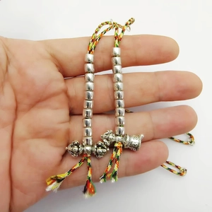 Detailed view of silver Vajra pestle and cylinder beads on braided colorful cord
