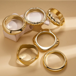 Minimalist irregular geometric gold-plated metal bangles set on stone props