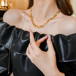 Detailed view of a gold leaf-shaped sequin tassel necklace on a model wearing black leather
