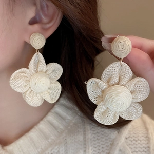 Bohemian cream raffia flower earrings shown on model for a trendy summer vacation look