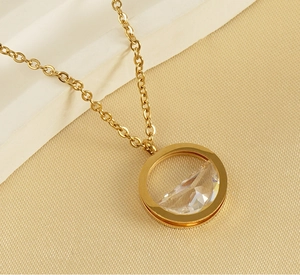 Close-up of golden stainless steel necklace featuring a round transparent crystal pendant