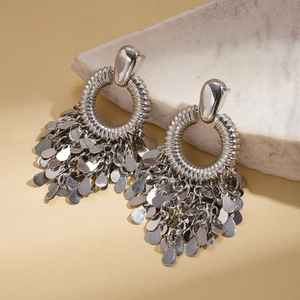 Détail de boucles d'oreilles argentées à pompons avec texture ronde sur marbre